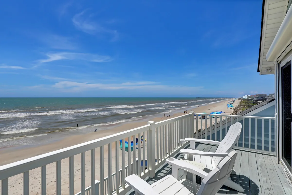 A serene oceanfront deck with two inviting deck chairs facing the vast ocean, set against a tranquil beach backdrop. The perfect setting for morning coffee, evening chats, or simply soaking in the view with friends or loved ones.