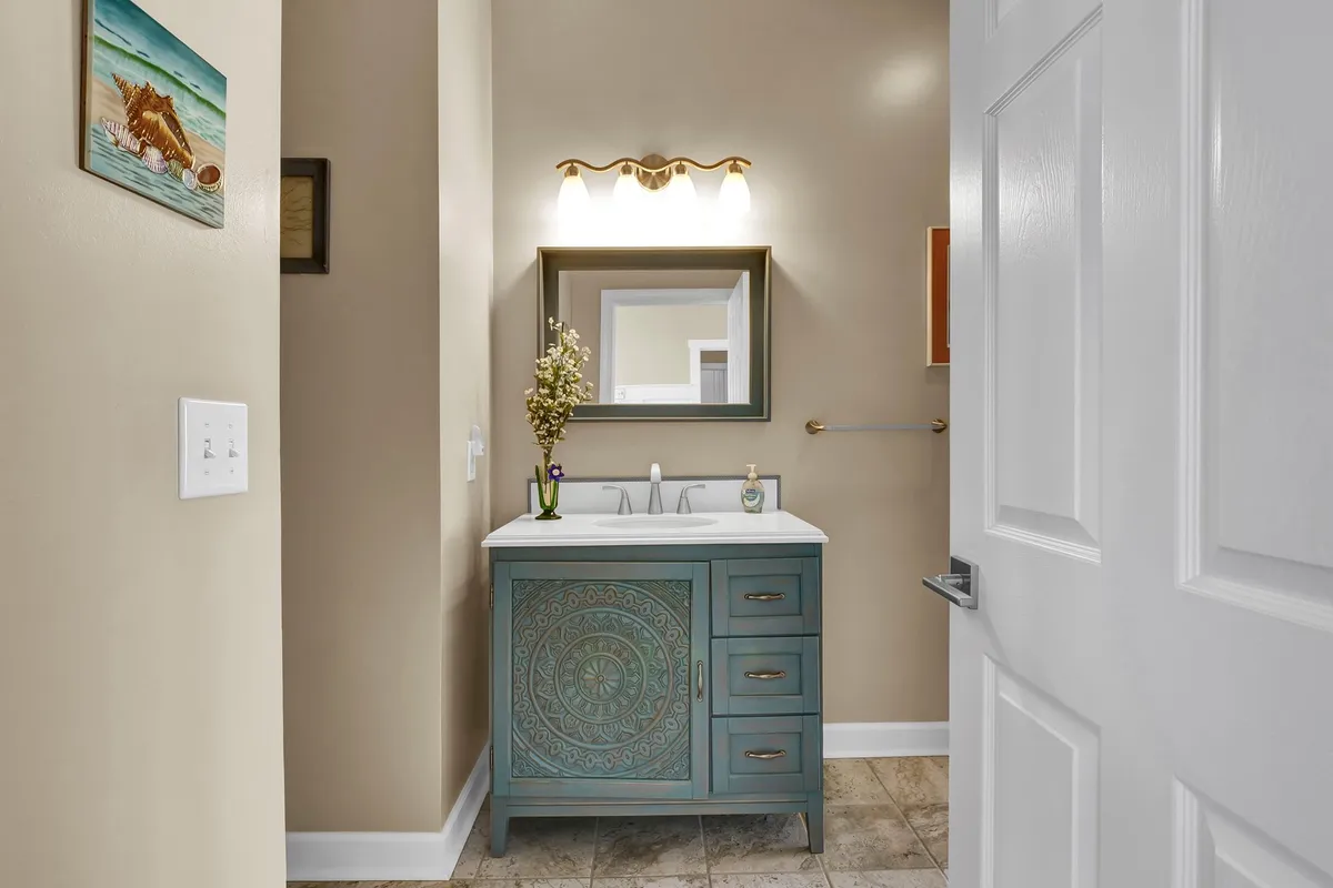 A serene bathroom featuring a decorative vanity with a framed mirror and a floral arrangement, setting a refreshing and calming space for self-care.