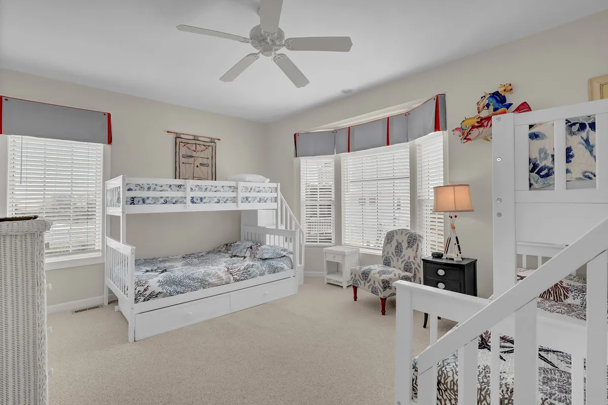 A playful, family-friendly bedroom setup with bunk beds, an armchair, and a window with sunlight filtering through, perfect for children, families, or friends.